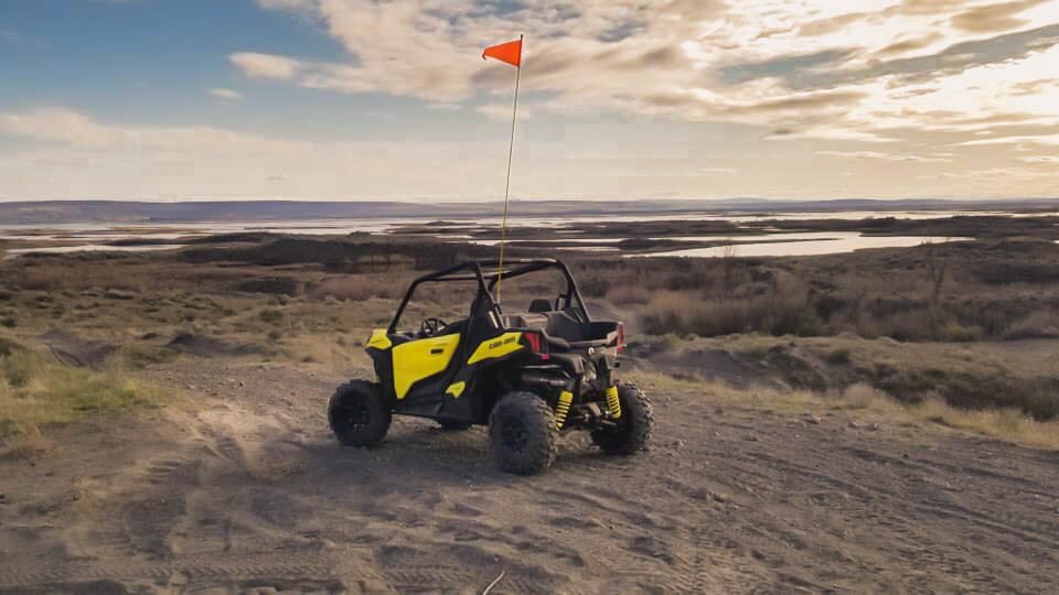 yellow atv in a sand dune next to a lake