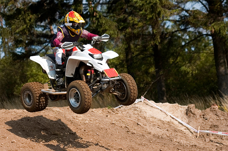 dirt 4 wheeler going over a jump in a ORV trail